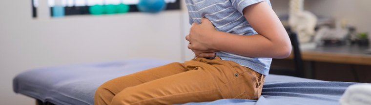 Close-up image of boy clutching his stomach in a doctor's room to illustrate constipation in children. Close-up image of boy clutching his stomach in a doctor's room to illustrate constipation in children.